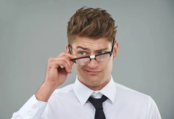 Er ist etwas skeptisch.... Ein junger Mann schaut skeptisch über seine Brille. — Stockfoto