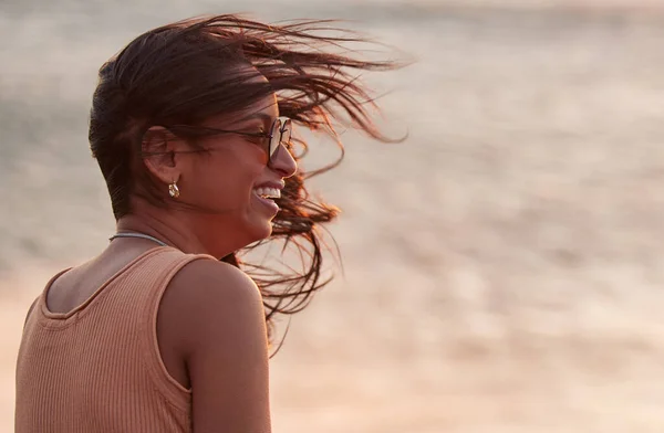 Det finns få saker som är renare än havsluften. Skjuten av en ung kvinna njuter av den friska strandluften medan solen går ner. — Stockfoto