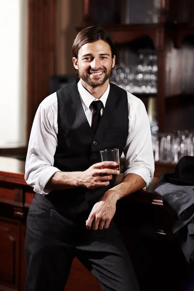 Relajarse mientras toma una copa. Retrato de un joven bien vestido de pie en un bar con una bebida. —  Fotos de Stock