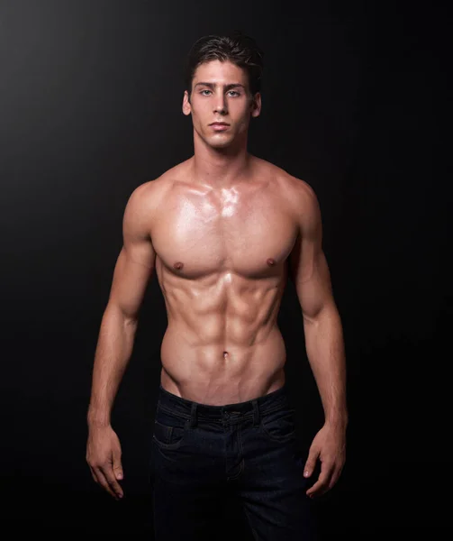 Hago músculos no excusas. Captura de estudio de un apuesto atleta joven con el pecho desnudo parado sobre un fondo negro. —  Fotos de Stock