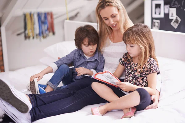 Διαβάζω με τη μαμά. Φωτογραφία μητέρας που διαβάζει με τα παιδιά της στο σπίτι. — Φωτογραφία Αρχείου
