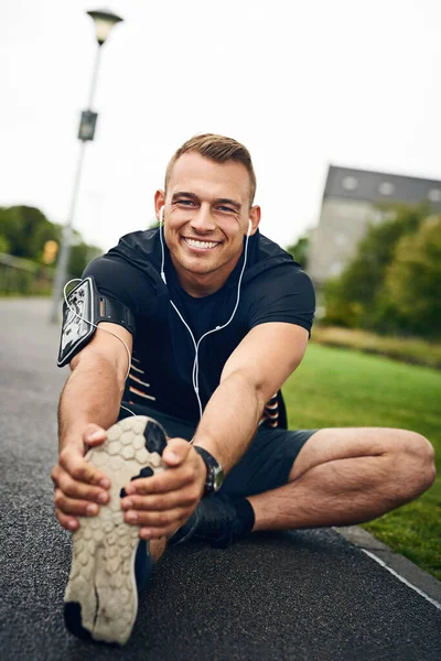 Haz la diferencia yendo a la distancia. Retrato de un joven deportivo que se extiende antes de una carrera al aire libre. — Foto de Stock