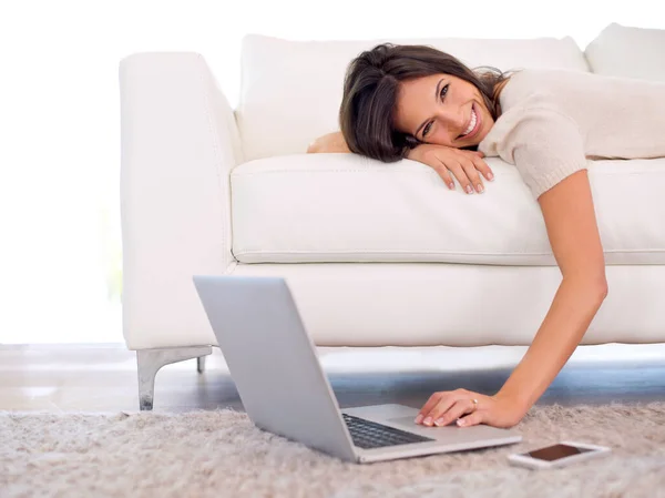Desfrutando de algum luxo, mantendo-se conectado. Tiro cortado de uma linda jovem deitada em um sofá usando um laptop. — Fotografia de Stock