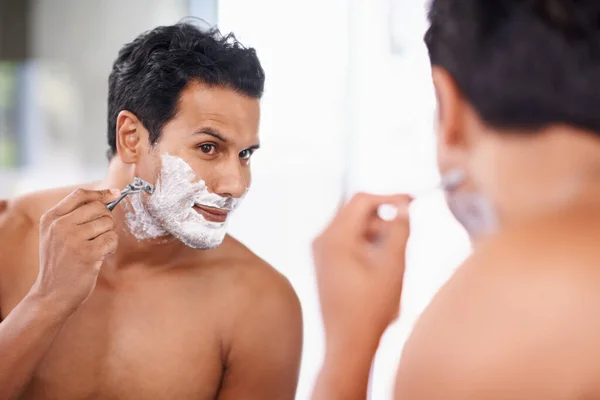 Die Damen lieben ein glattes Gesicht. Ein schöner junger Mann rasiert sich im Badezimmer. — Stockfoto