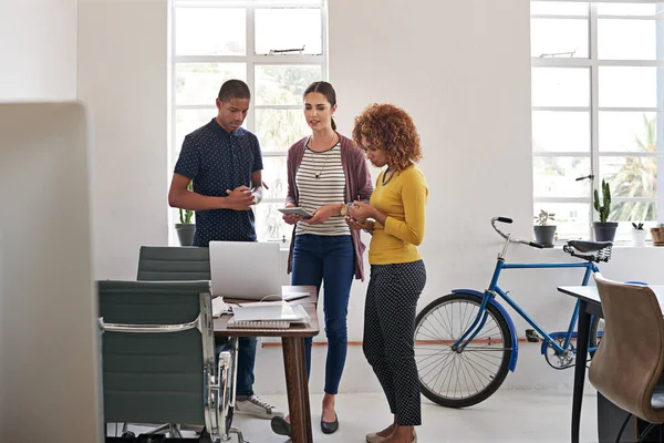 stock image They owe their success to teamwork. Shot of a group of colleagues having an informal meeting with a laptop in a modern office.