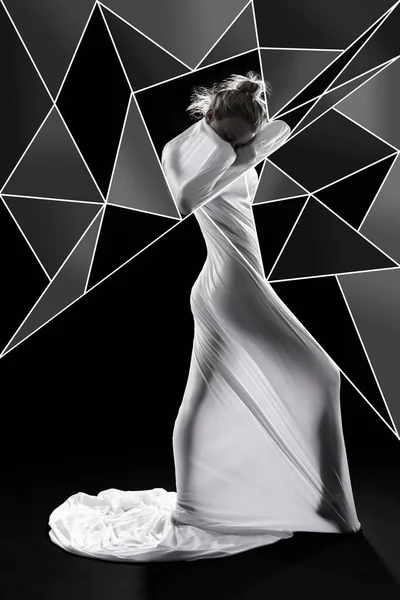 Deixe sua beleza emergir do esconderijo. Estúdio de uma mulher envolto em tecido e rodeado por formas geométricas contra um fundo preto. — Fotografia de Stock