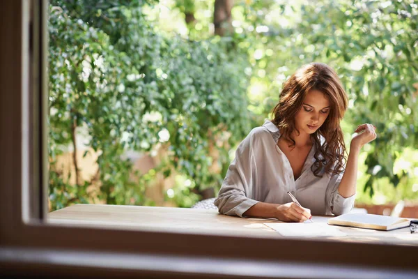 Ze wordt een beroemde schrijfster. Shot van een aantrekkelijke jonge vrouw schrijven in een ontspannen omgeving buiten. — Stockfoto