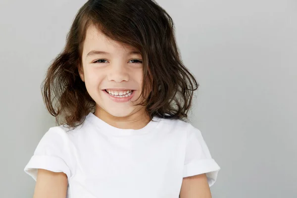 Doce sorriso. Retrato de um menino sorridente contra um fundo cinzento. — Fotografia de Stock