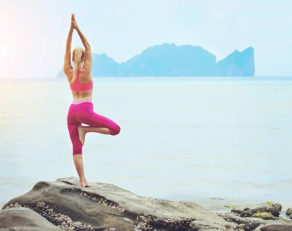 Het vinden van innerlijke rust aan zee. Rearview shot van een jonge vrouw doet yoga op een tropisch strand. — Stockfoto