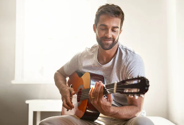 A aperfeiçoar o seu talento musical. Tiro de um jovem bonito tocando guitarra em casa. — Fotografia de Stock