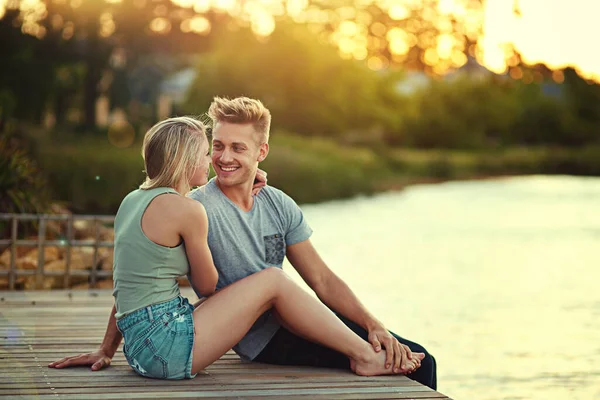 Quero passar todos os meus dias contigo. Tiro de um jovem casal carinhoso sentados juntos em um lago fora. — Fotografia de Stock