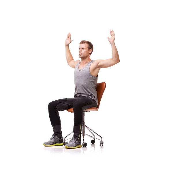 Rozciąga klatkę piersiową. Przystojny młody mężczyzna ubrany w strój gimnastyczny i rozciągający się siedząc w fotelu biurowym na białym tle. — Zdjęcie stockowe