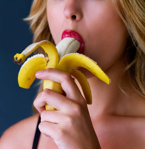 Algo saboroso para satisfazer o desejo. Estúdio recortado de uma jovem mulher comendo uma banana sugestivamente contra um fundo escuro. — Fotografia de Stock