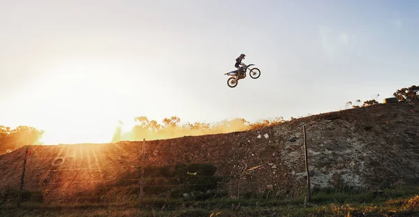 Theres not a competitor in sight. Shot of a motocross rider going over a jump during a race. — Stock Photo, Image