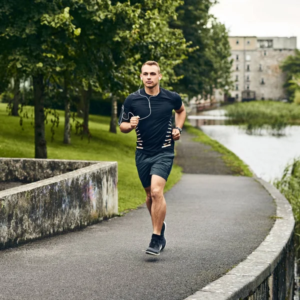 Estás cada paso más cerca de tus metas. Tiro de un joven deportivo haciendo ejercicio al aire libre. — Foto de Stock