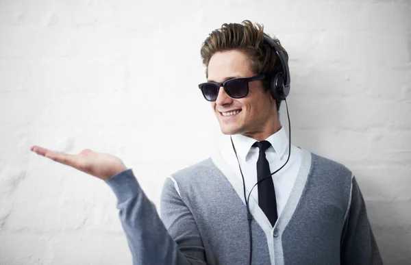Moderní technika a váš produkt. Módní mladý muž natahuje dlaň, zatímco poslouchá hudbu na sluchátkách. — Stock fotografie