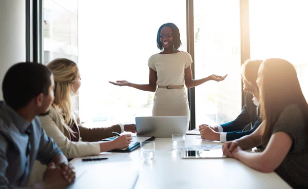 Tiene toda su atención. Fotografía de una joven empresaria liderando a su equipo en una reunión en la oficina. — Foto de Stock