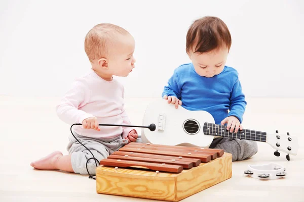 They have the makings of a successful band. Shot of two adorable babies playing with toy musical instruments. — Stock Photo, Image