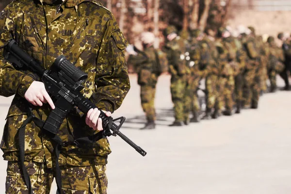 Redo för allt. En soldat står med ett gevär och hans medsoldater i bakgrunden. — Stockfoto