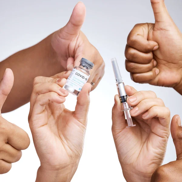 Το να φροντίζεις τον εαυτό σου δεν είναι εγωιστικό. Στούντιο πλάνο μιας ομάδας ανθρώπων που δείχνουν αντίχειρες και κρατώντας το εμβόλιο σε γκρι φόντο. — Φωτογραφία Αρχείου