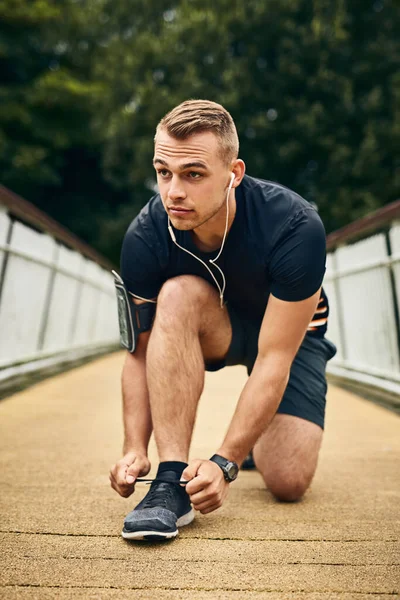 Prepárate para correr tu corazón. Tiro de un joven deportivo atándose los cordones mientras hace ejercicio al aire libre. — Foto de Stock