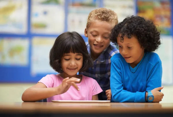 Εκπαίδευση με τη βοήθεια δισκίων. Τρεις μαθητές που εργάζονται σε μια ψηφιακή ταμπλέτα στην τάξη. — Φωτογραφία Αρχείου
