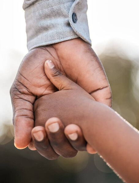 I will guide you through life. Closeup shot of a father holding his sons hand while walking together outdoors.