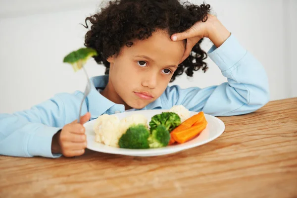 Brócoli otra vez. Un disparo de un niño sin impresionar sentado frente a un plato de verduras. — Foto de Stock