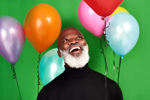 Vive tu vida y sé feliz. Estudio de un hombre posando sobre un fondo verde con globos a su alrededor. — Foto de Stock