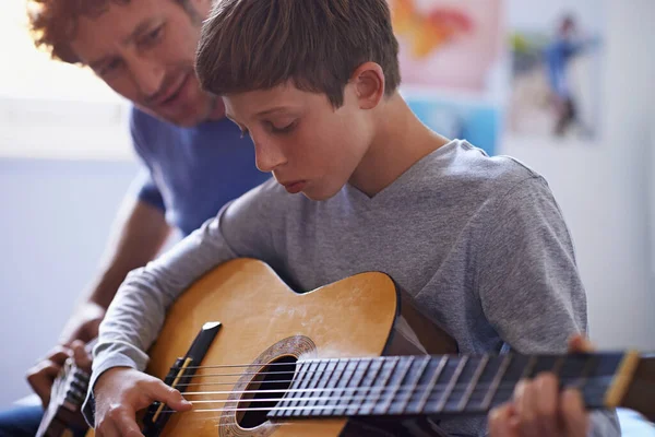 Studying the strings. Shot of a boy learning to play guitar from his father. — Stock Photo, Image