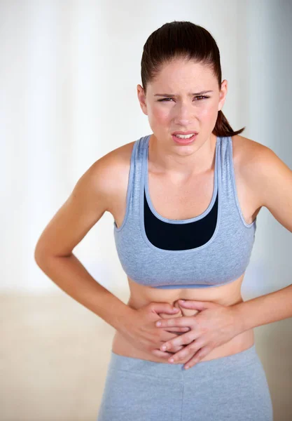 Dolore allo stomaco. Ritratto di una giovane donna attraente che tiene lo stomaco dolorante. — Foto Stock