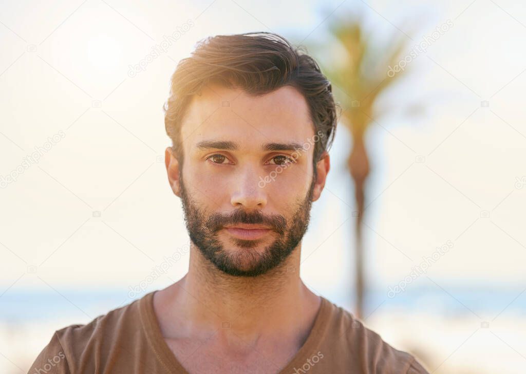 Hes a mediterranean man. Portrait of a handsome young man standing outside on a sunny day.