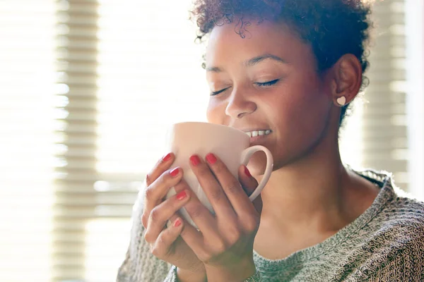 행복은 갓 끓인 커피 냄새입니다. 한 젊은 여자가 커피를 마시면서 집에서 쉬고 있는 장면이 걸려 있다. — 스톡 사진