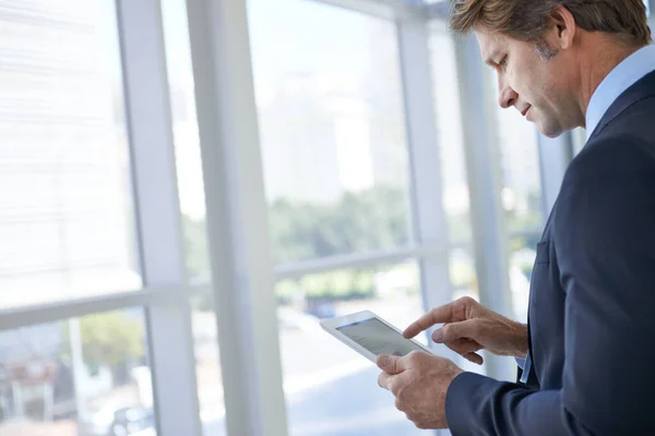 Des applications professionnelles essentielles entre vos mains. Vue d'un homme d'affaires mature debout dans un couloir de bureau à l'aide d'une tablette numérique. — Photo