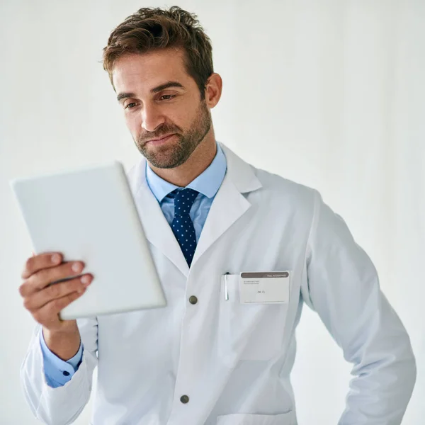 Rimanere aggiornati sul mondo della medicina. Colpo ritagliato di un bel giovane medico che legge da un tablet digitale nel suo ufficio. — Foto Stock