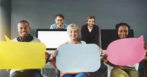 Un anuncio de la oficina. Fotografía de un grupo diverso de personas sosteniendo burbujas de habla en una oficina moderna. —  Fotos de Stock