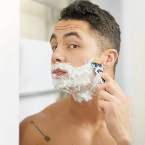 Keeping a clean face. Cropped shot of a young man shaving his beard. — Stock Photo, Image
