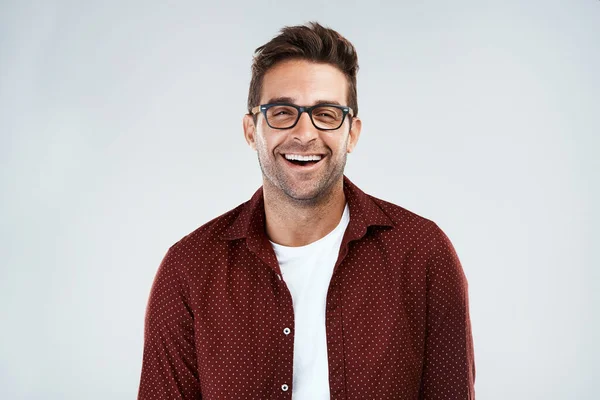 Morsomt og smart. Portrett av en munter ung mann med briller og smil mens han står mot en grå bakgrunn. – stockfoto
