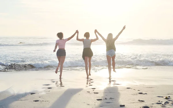 Det er ingen bedre måte å kjøle seg ned på. Skutt av tre venner som tilbringer dagen på stranden. – stockfoto