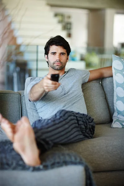 Comprobando lo que hay en la tele. Retrato de un hombre sentado en su sofá viendo la televisión. — Foto de Stock