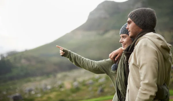 Esta vista es impresionante. Una joven pareja admirando la vista mientras caminaba durante el invierno. —  Fotos de Stock