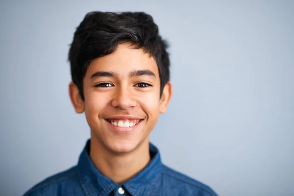 Hes one super confident kid. A cute young preteen boy standing and smiling against a grey background. — Stock Photo, Image