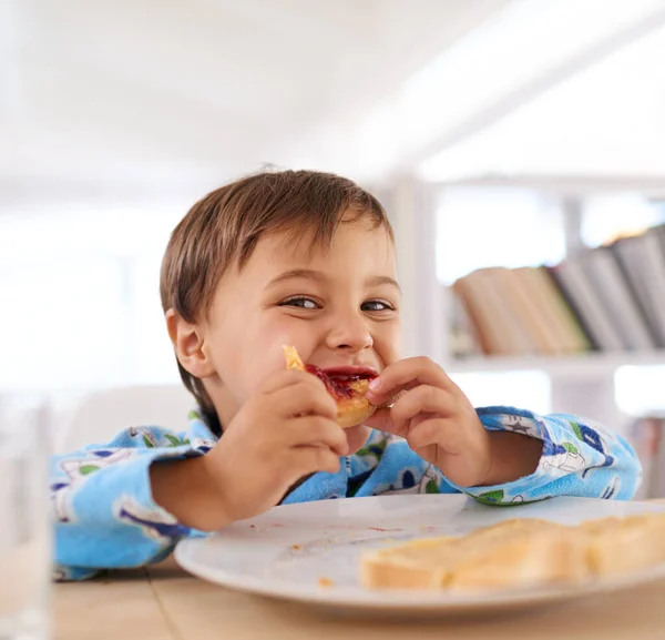 Rakastan hilloa paahtoleivällä eniten. Söpö pieni poika syö aamiaista. — kuvapankkivalokuva