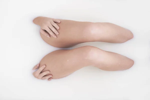 Hedvábné a mléčné. Vystřižený záběr ženských nohou v mléčné lázni. — Stock fotografie