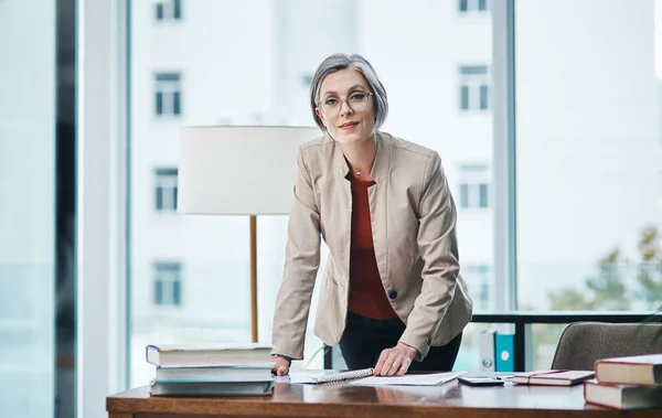 Nie widziałem, żebyś tam stał. Przycięty portret atrakcyjnej dojrzałej bizneswoman stojącej i czytającej dokumenty przy biurku w swoim biurze. — Zdjęcie stockowe
