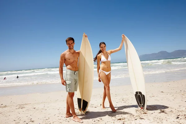 Juntos pueden hacer cualquier cosa. Fotografía de una joven pareja sosteniendo tablas de surf en la playa. — Foto de Stock