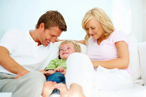 Family of three sitting on sofa. Happy couple sitting on a sofa with their young son. — Stock Photo, Image