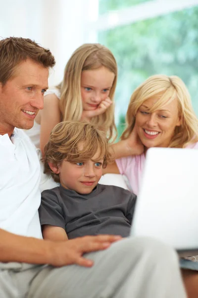 Navegando por la web juntos. Feliz familia joven usando un ordenador portátil juntos en el sofá en casa. — Foto de Stock