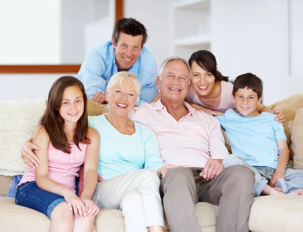 Pasando por la vida juntos - Apoyo Familiar. Tres generaciones de familia sentados juntos cariñosamente en el sofá del salón. —  Fotos de Stock