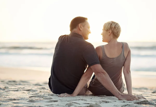 Regarder les marées s'accumuler avec celle que j'aime. Un couple aimant assis sur la plage - vue arrière. — Photo